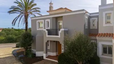 a house with a palm tree in front of it at V4 Duplex Quinta do Lago Sal in Quinta do Lago