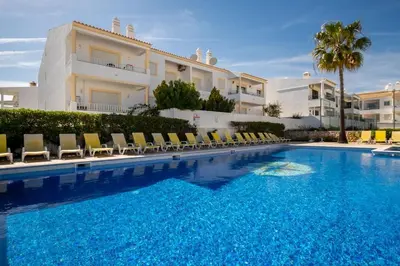 a large swimming pool with chairs and a building at Casa Biamar in Albufeira