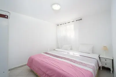 a white bedroom with a pink bed and a window at Casa Biamar in Albufeira