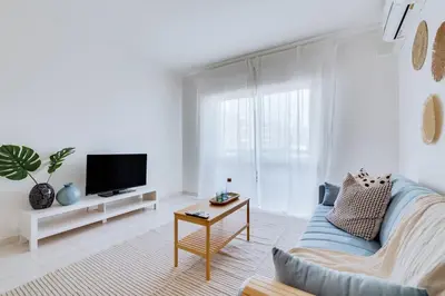 a living room with a blue couch and a tv at Brisa Algarvia 2 in Faro
