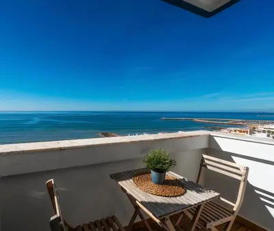 a table and chairs on a balcony with the ocean at Ocean View Apartment Steps to Beach Vil15m Faro25m in Quarteira