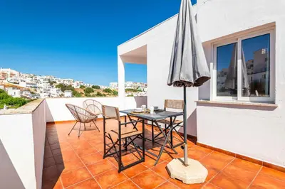 a table and chairs on a balcony with an umbrella at Downtown Rooftop 1 Bedroom Apartment in Albufeira