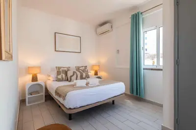 a bedroom with a bed with two lamps and a window at Downtown Rooftop 1 Bedroom Apartment in Albufeira