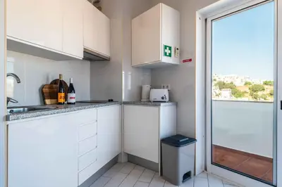 a small kitchen with white cabinets and a window at Downtown Rooftop 1 Bedroom Apartment in Albufeira