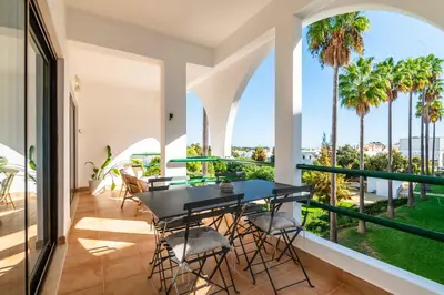 a balcony with a black table and chairs and palm trees at Casa Alonso 2 Bedroom Apartment with Pool in Albufeira