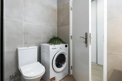 a bathroom with a washing machine and a toilet at Maya Vilamoura - City center by HD PROPERTIES in Vilamoura