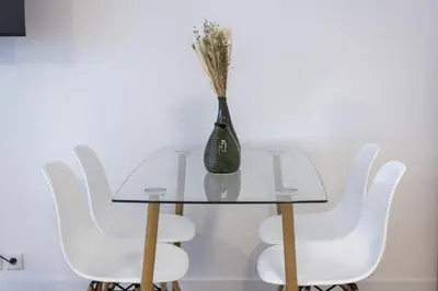 a glass table with white chairs and a vase on it at Maya Vilamoura - City center by HD PROPERTIES in Vilamoura