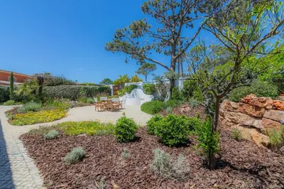 a garden with a stone wall and a table at Golf&Mar By Garvetur Villas in Loulé