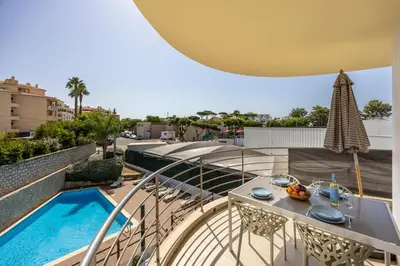 a balcony with a table and a swimming pool at Casa A in Olhos de Água
