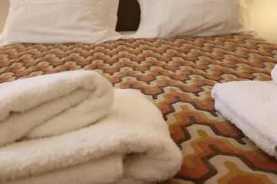 a bed with a pile of white towels on it at Casa Malpique in Albufeira