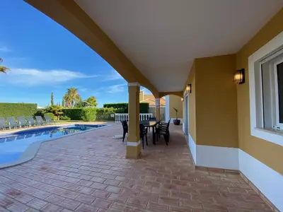 a patio with a table and chairs next to a pool at Villa 