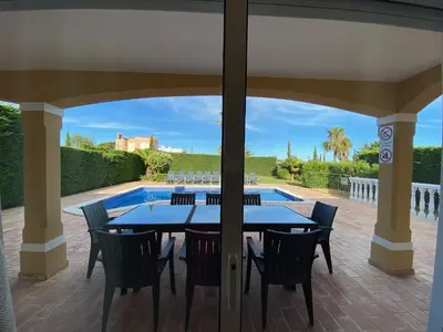 a patio with a table and chairs and a pool at Villa 