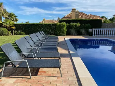 a row of lounge chairs next to a swimming pool at Villa 