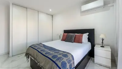 a bedroom with a bed and a white wall at Bright 1BDR Flat in Albufeira by LovelyStay in Albufeira