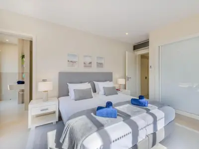 a white bedroom with a large bed with blue pillows at Apartment Pine Hills Diadema-16 by Interhome in Vilamoura