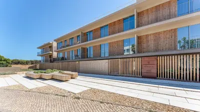 an apartment building with benches in front of it at Luxury Flats with Pool in Quarteira by LovelyStay in Quarteira