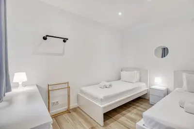 two beds in a room with white walls and wooden floors at Sunshine Apartment in Vilamoura