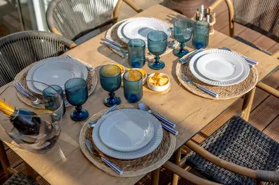 a wooden table with plates and wine glasses on it at Micului Refugiu in Albufeira