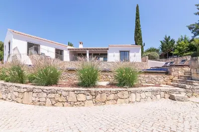 a house with a stone retaining wall in front of it at Casa Velha in Loulé