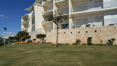 a building with a tree in front of a yard at Luxurious T2 with Pool & Breathtaking Ocean Views by BeCherish in Albufeira