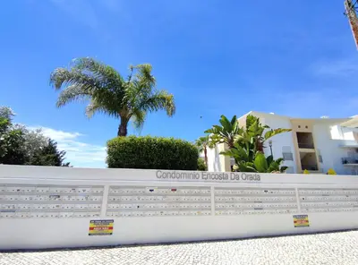 a fence in front of a house with a palm tree at Luxurious T2 with Pool & Breathtaking Ocean Views by BeCherish in Albufeira
