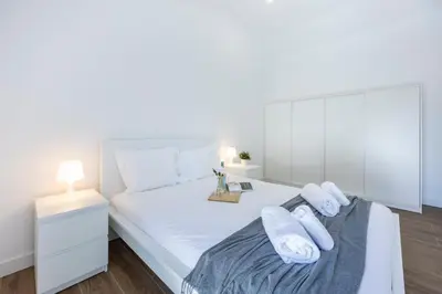 a bedroom with a white bed with towels on it at Alfamar Beach Apartment in Albufeira