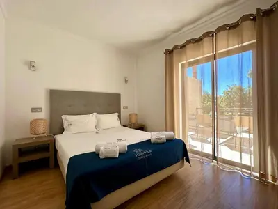 a bedroom with a bed and a large window at Janelas do Oceano by FHR in Quarteira
