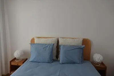 a bed with two blue pillows and two night stands at Blue House - City's Heart in Faro