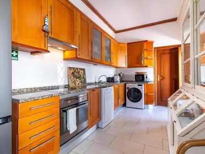 a kitchen with wooden cabinets and a washer and dryer at Casa Algarvia Senhorial by Stay ici Algarve Holiday Rental in Albufeira