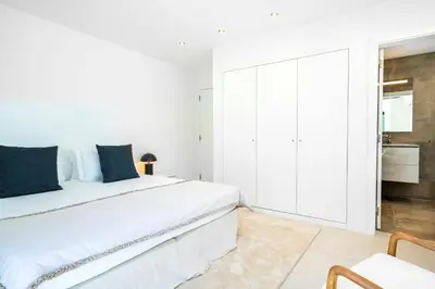 a white bedroom with a large bed with blue pillows at Villa Cyan by SAPvillas in Vilamoura