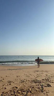 a woman walking on the beach with a surfboard at Villa mar e Serra in Loulé