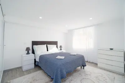 a white bedroom with a bed and a dresser at Casa Biabella in Albufeira