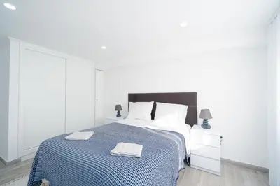 a white bedroom with a bed with two towels on it at Casa Biabella in Albufeira