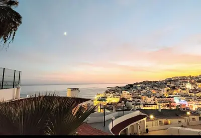 a view of a city and the ocean at sunset at Albufeira Pescadores Sea view in Albufeira