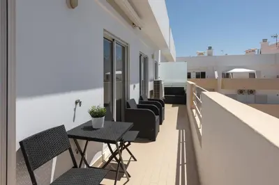 a balcony with chairs and a table on a building at Golfinho - Sea view with pool by HD in Quarteira