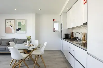 a kitchen with a glass table and white chairs at Moura One - Condominium with pool by HD in Vilamoura