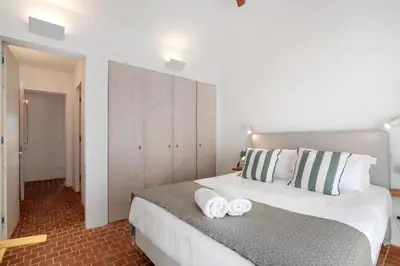 a bedroom with a large white bed with towels on it at Espuma do Tempo in Quarteira