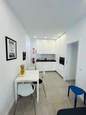 a white kitchen with a white table and chairs at Casa Eliz Modern Comfort in the center of Faro in Faro