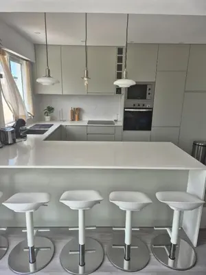 a kitchen with a white counter and four stools at Beautiful View Apartment in Quarteira