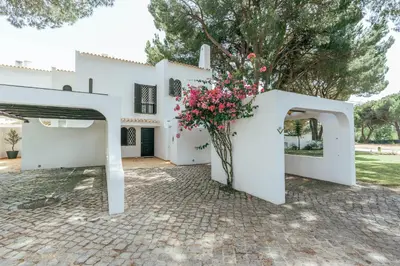 a white house with a courtyard with flowers at Serenity Villa Vilamoura in Quarteira