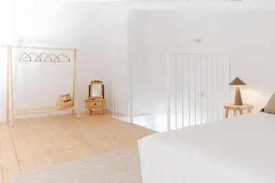 a white bedroom with a bed and a mirror at Casa Majú - Algarve in Valados