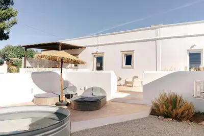 a patio with chairs and an umbrella and a house at Casa Majú - Algarve in Valados