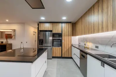 a kitchen with white cabinets and stainless steel appliances at Stylish Algarve Retreat- Priv. Pool & Beach Nearby in Quarteira