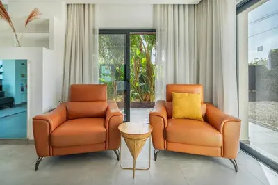 two orange chairs and a table in a living room at Stylish Algarve Retreat- Priv. Pool & Beach Nearby in Quarteira