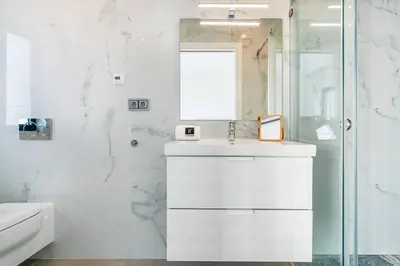a white bathroom with a sink and a shower at Stylish Algarve Retreat- Priv. Pool & Beach Nearby in Quarteira