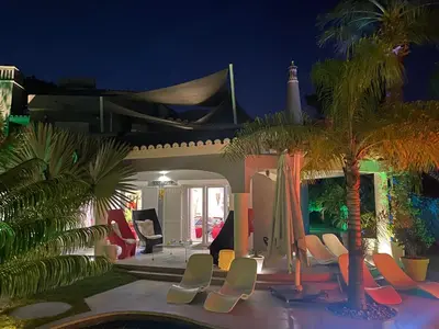 a house with chairs and palm trees at night at Villa Karolina in Quarteira