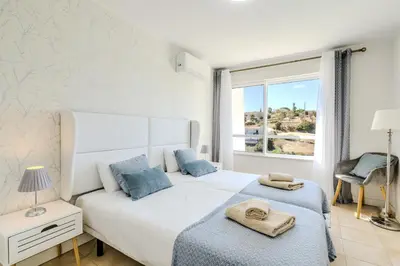 a bedroom with a white bed with blue pillows and a window at #339 Albufeira Terras Novas N 4 By Home Holidays in Patroves