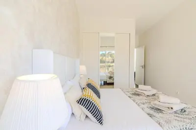 a white bedroom with a bed and a lamp at #339 Albufeira Terras Novas N 4 By Home Holidays in Patroves