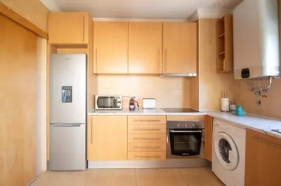 a kitchen with wooden cabinets and a white refrigerator at Dunes Apartment - Near the Beach in Guia