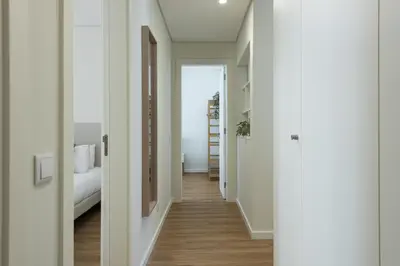 a hallway leading to a bedroom with white walls and wood floors at Mira Mar 2 - Near the beach by HD in Quarteira